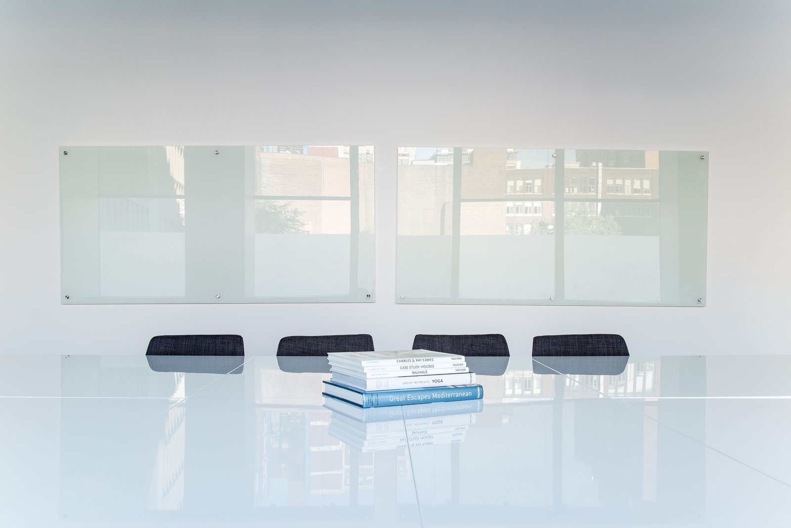 Pile de livres design posés sur une table de réunion blanche — image d'illustration des ressources documentaires disponibles pour les CGP partenaires