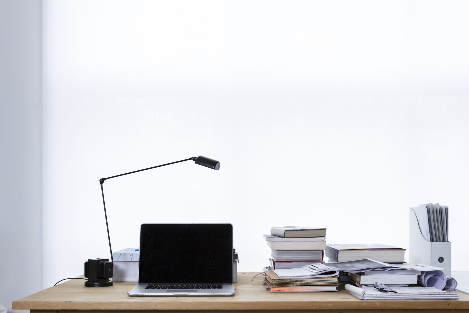 Laptop pro sur bureau clair avec livres et documents — image d'illustration du CRM partenaires mis à disposition par la Financière Outre-Mer